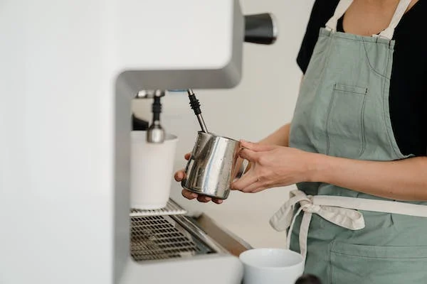 a lady using the milk frother