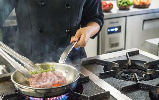 a cook frying the steak with a ss pan