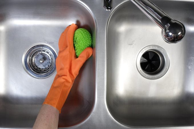 a person cleaning the ss sink with soft  brush