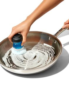 a person washing the ss pan with soft brush