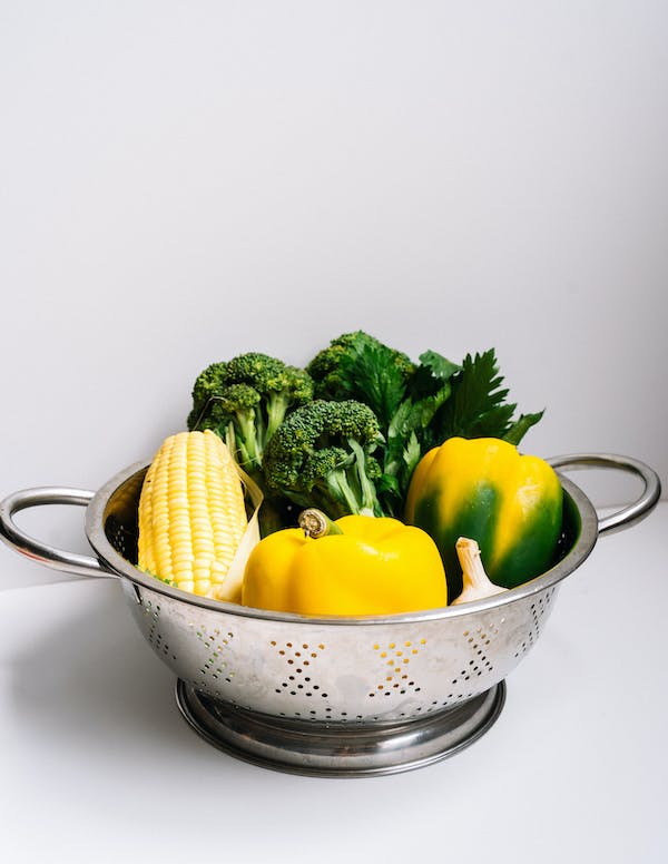 stainless steel filter basin with some vegetable in it